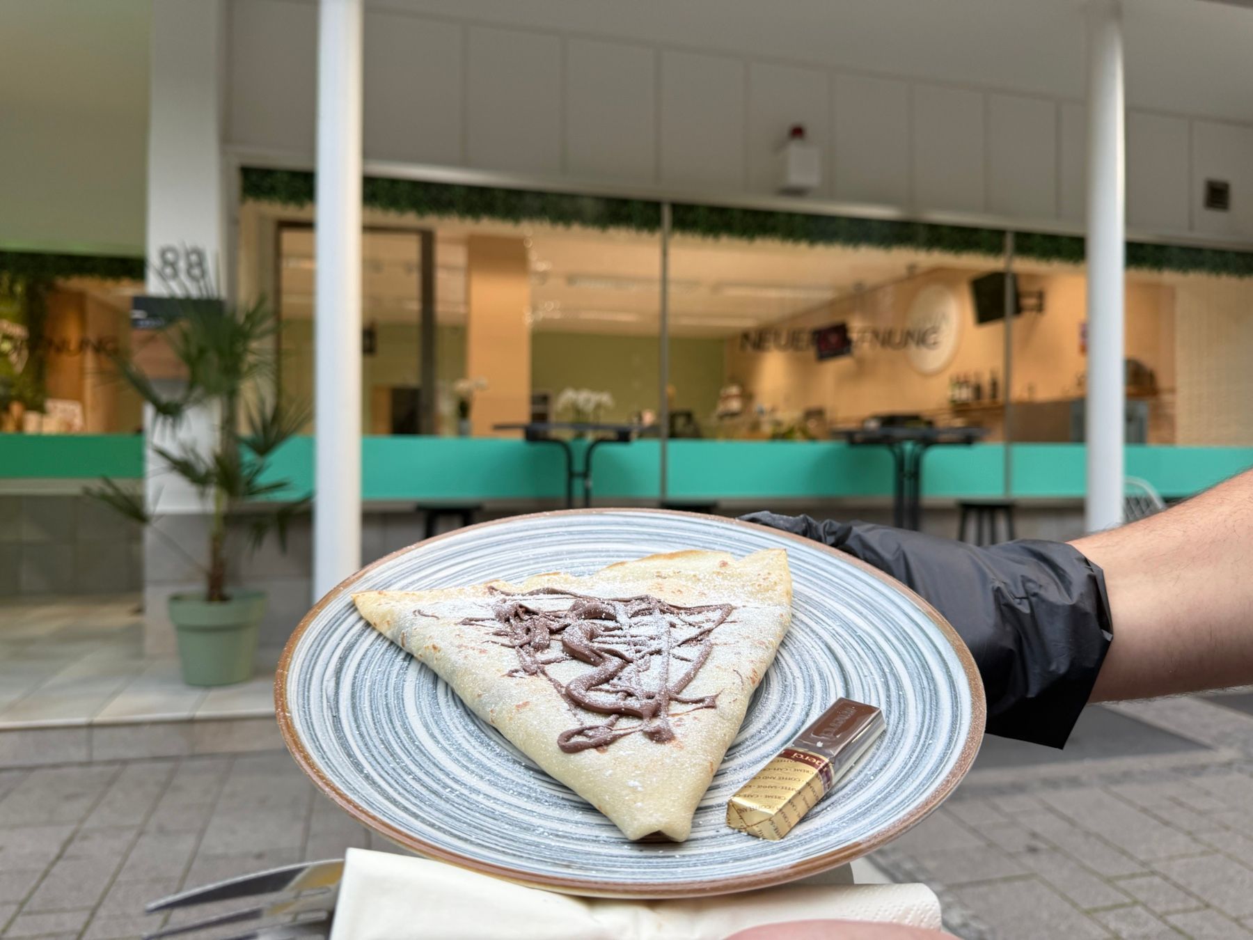 VIVA-Crêpe mit Schokoladensauce und Puderzucker vor unserem Laden